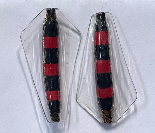 A winged fishing lure that has red and black bands alternating from top to bottom